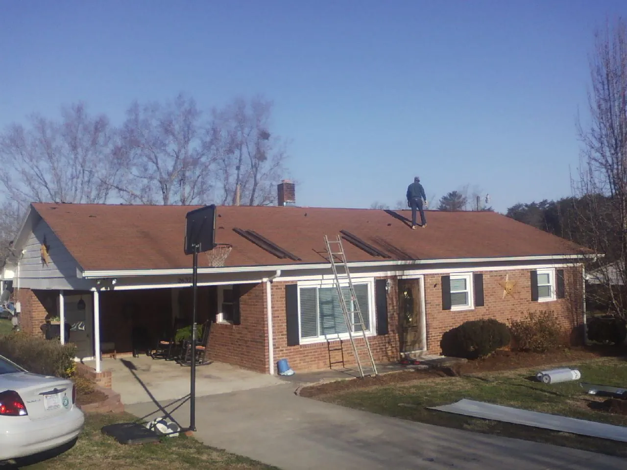 Roofer stripping a shingle roof on a brick ranch before metal panels in Mentcle