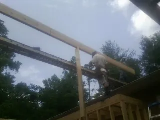 Carpenter setting a ridge beam over a new addition frame — Ice Dam Removal by Roofing Brothers in Mentcle