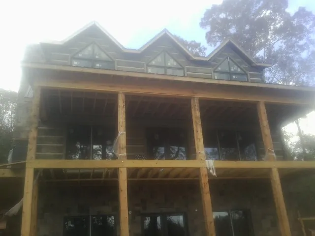 Dormers and porch framing on a large log home under construction — Roof Coating work by our crew in Mentcle