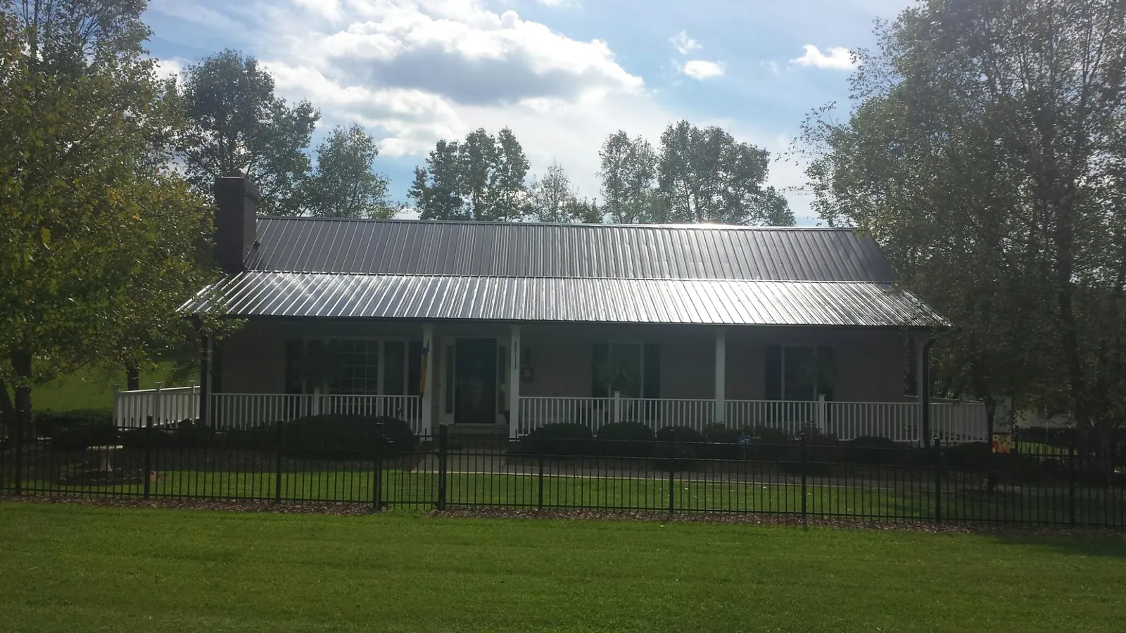 Gray metal roof on a brick ranch with a full width front porch — Gutter Guard Installation work by our crew in Mentcle
