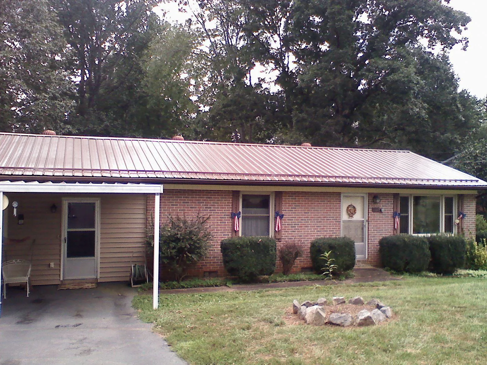 Bronze metal roof and carport on a brick ranch home — Roof Repair work by our crew in Mentcle