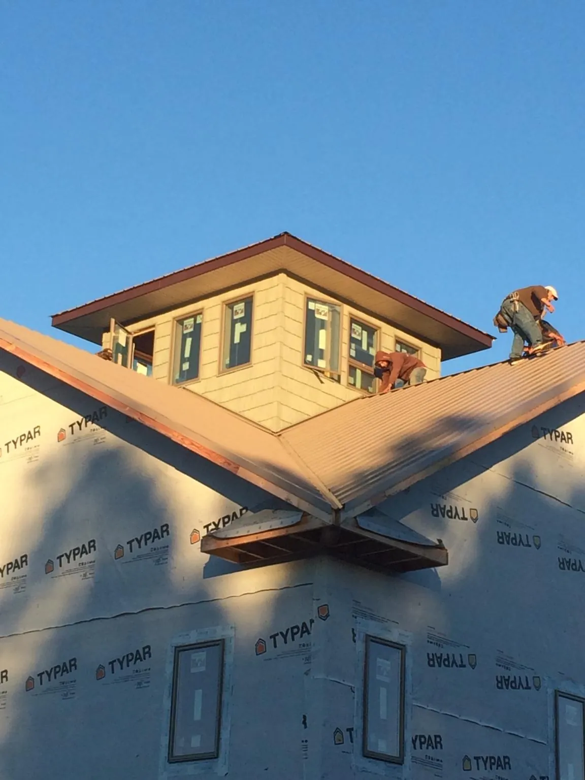 Roofers working around a rooftop cupola on a new metal roof at sunset — Roof Waterproofing in Mentcle by Roofing Brothers